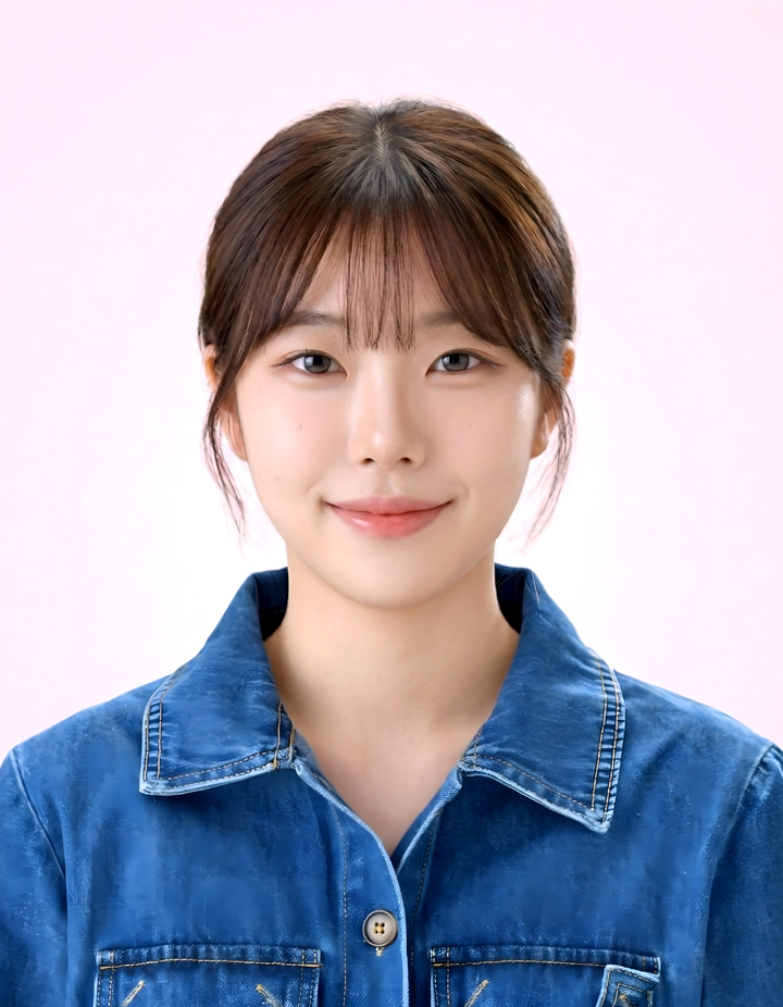 파란색 데님 셔츠를 입은 여성의 증명사진. 연분홍색 배경에서 자연스럽게 묶은 머리와 가벼운 앞머리, 부드러운 미소로 밝고 편안한 인상을 표현한 사진.