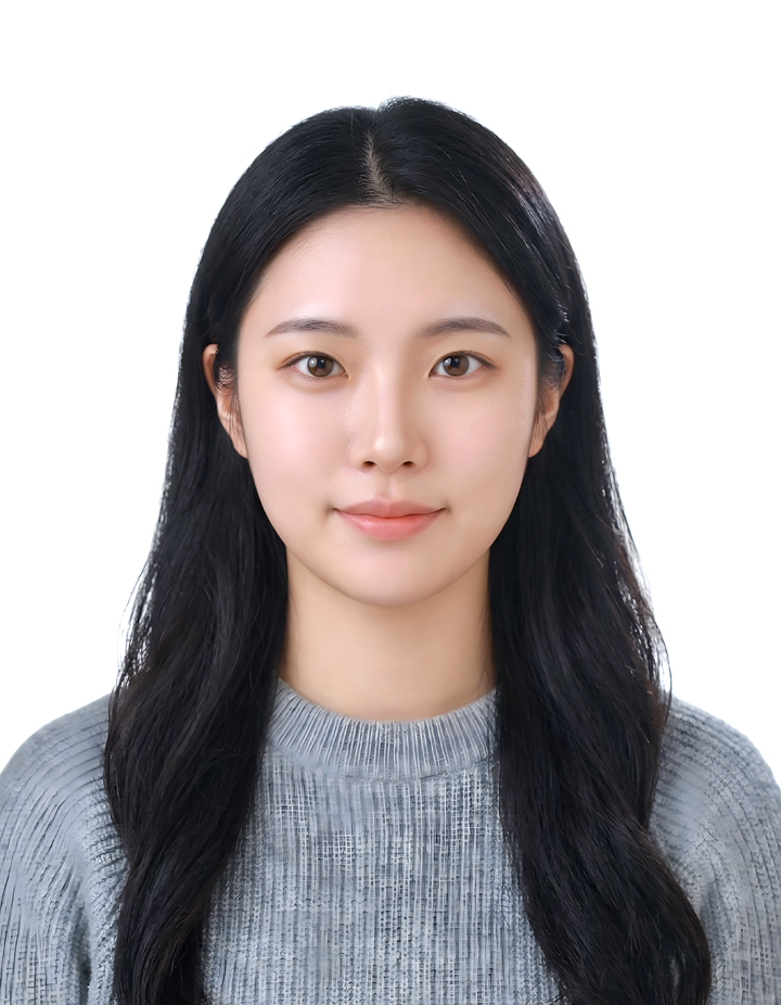 흰색 배경에서 회색 니트 상의를 입은 여성의 증명사진. 긴 검은색 웨이브 헤어스타일과 자연스러운 미소로 단정하고 차분한 인상을 표현한 사진.